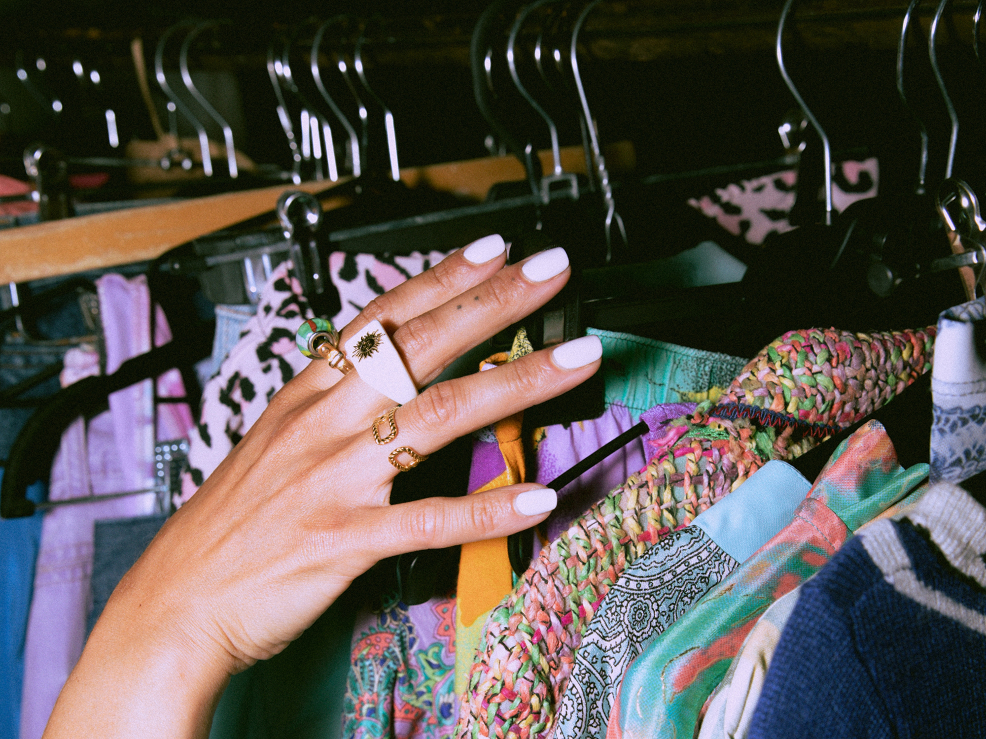 Customer hand browsing colorful clothes – immersive retail experience – scent marketing in fashion store