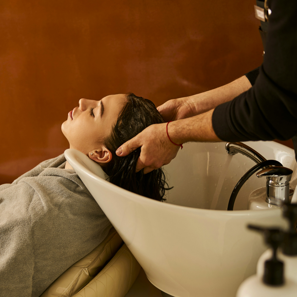 Client receiving hair treatment in luxury beauty salon with scent experience.