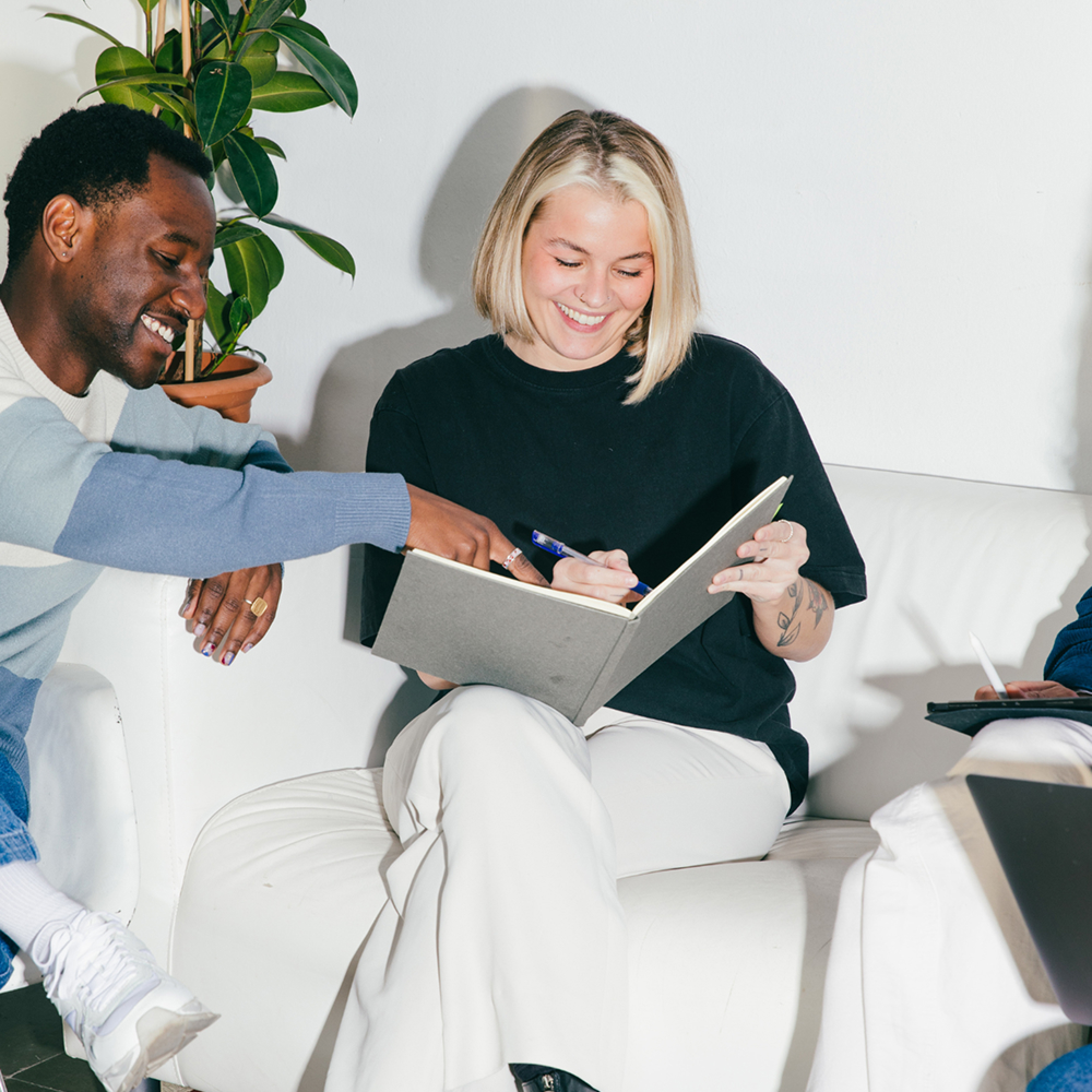 Two smiling colleagues collaborate at the office – friendly and approachable team ready to assist you.