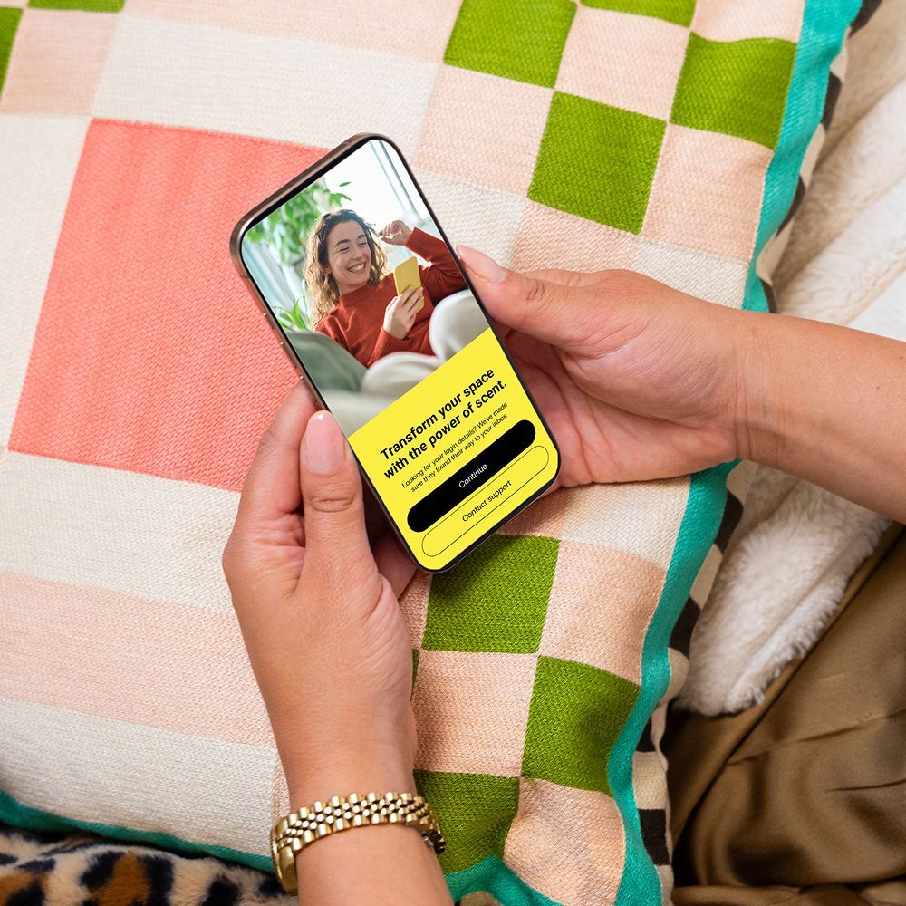 Retail staff adjusts scent settings via smartphone for a personalized in-store scent experience.