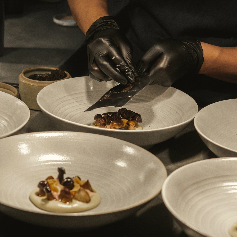 Professional chef working diligently in a restaurant kitchen, contributing to a multisensory dining experience including scent