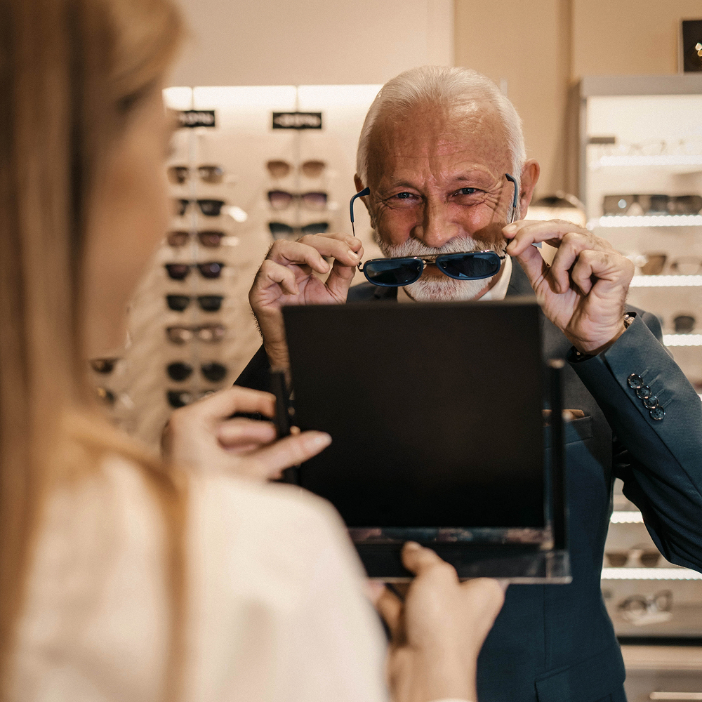 Customer experiencing scent in eyewear store – scent marketing in retail – man smelling glasses for a multisensory shopping experience